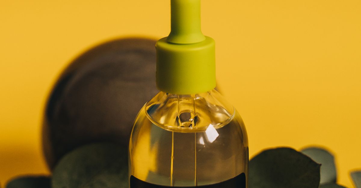 Glasflaske med æterisk olie og grønne blade – Tea tree olie mod bumser – Trondahl Skincare