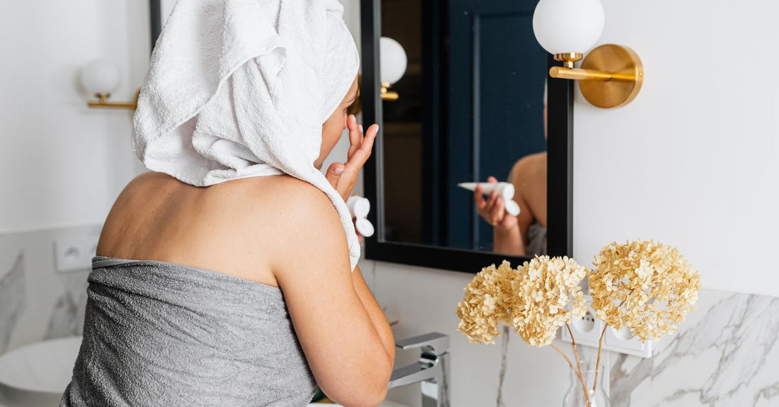 Kvinde påfører ansigtscreme ved spejl – natcreme guide og hudens reparation – Trondahl Skincare
